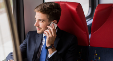 an employee in a suit talks on the phone while taking a commuter shuttle service